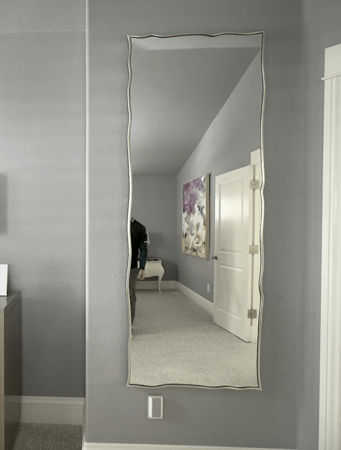 Mirror installation services in Colorado featuring a large mirror in a modern home with framed photos on a dresser